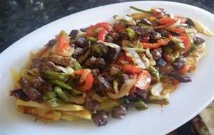 Ternera Con Pimientos Y Cebolla Sobre Cama De Patatas Fritas.