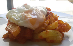 Patatas En Salsa De Tomate Y Huevo Frito.
